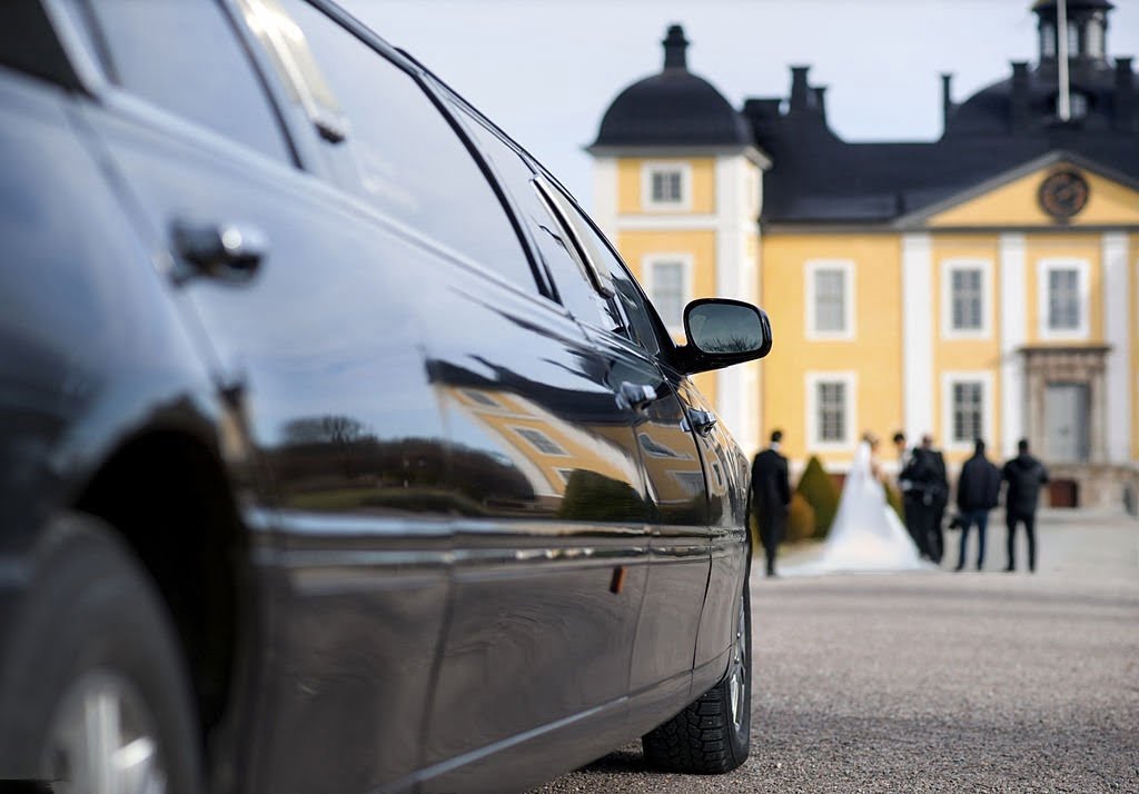 Wedding Chauffer Service - Black limo waiting for bride and groom outside the mansion