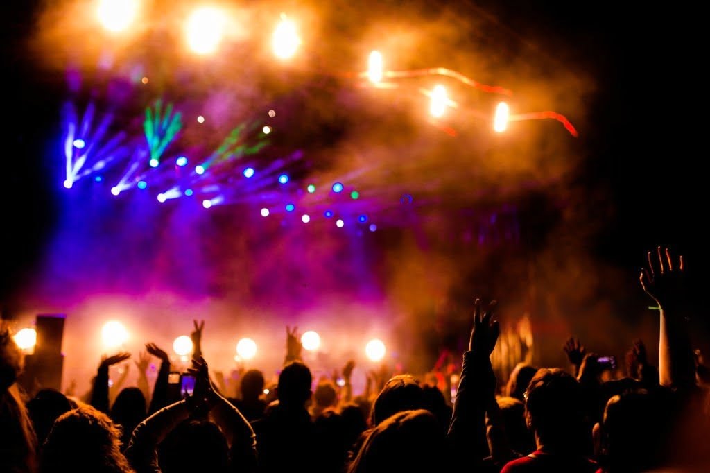 Concert Chauffer Service - Crowd dancing with their hands up in concert at night